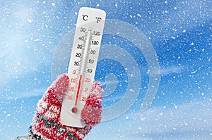 White celsius and fahrenheit scale thermometer in hand. Ambient temperature 0 degrees