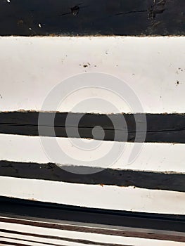 White cement rough wall background with black wooden slat horizontal slats. Detail of beams, lumber and other construction
