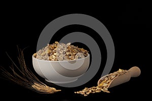 white ceramic bowl with muesli ,wooden spoon and ear of wheat