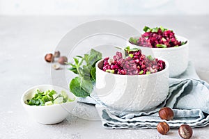 White ceramic bowls with buckwheat, beetroot, nuts and herbs warm salad, light grey concrete background.