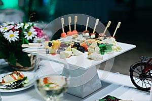 A white ceramic coaster with hors d`oeuvres on the wedding table.