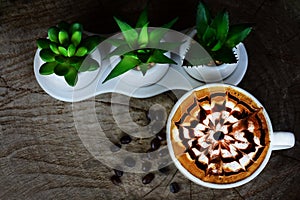 White ceramic coffee cup with cappuccino and latte art placed on an old wooden floor