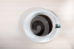 A white ceramic cup with black coffee with smoke