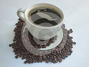 White ceramic cup with coffee and coffee beans on a saucer