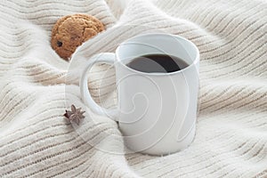 White ceramic cup of coffee without cream with cosy blanket, cookie and star anice