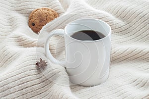 White ceramic cup of coffee without cream with cosy blanket, cookie and star anice photo