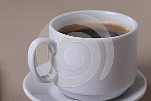 A white ceramic cup for hot beverage on light beige background