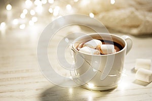White ceramic cup of hot cocoa with marshmallows on white wooden background