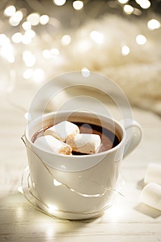 White ceramic cup of hot cocoa with marshmallows on white wooden background