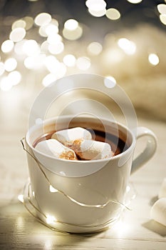 White ceramic cup of hot cocoa with marshmallows on white wooden background