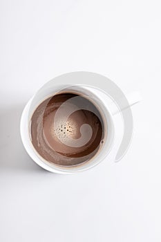 White ceramic cup of hot cocoa on top of white marble background, top view