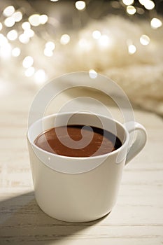 White ceramic cup of hot cocoa on white wooden background