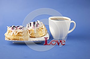 White ceramic cup of hot coffee and sweet pastries on blue background