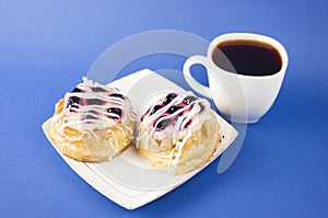 White ceramic cup of hot coffee and sweet pastries on blue background