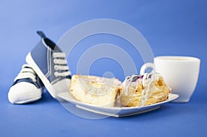 White ceramic cup of hot coffee and sweet pastries on blue background