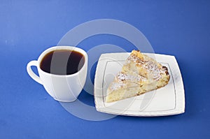 White ceramic cup of hot coffee and sweet pastries on blue background