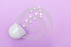 White ceramic cup isolated on purple background with cubed sugar, food concept