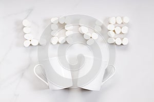 White ceramic cup and love-shaped marshmallows on white background