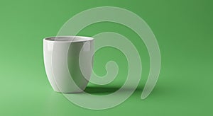 A white ceramic cup sits on a bright green background. The cup has a smooth, glossy