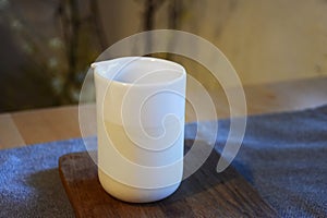 White Ceramic cup on wooden plate and on tablen