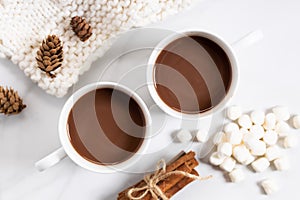 White ceramic cups of hot cocoa on top of white marble background, top view