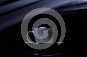 White ceramic mug on a black wooden table illuminated by natural light