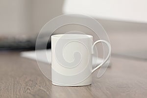 White ceramic mug and computer on wooden table at workplace