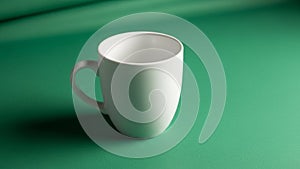 White ceramic mug on a green surface positioned slightly to the left