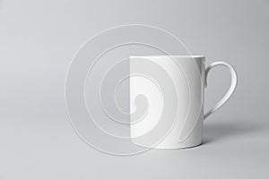 White ceramic mug on light grey background. Space for text