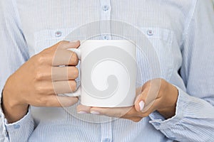 White ceramic mug mockup. Girl wears blue shirt Holds a Cup of cocoa. Space for your text branding
