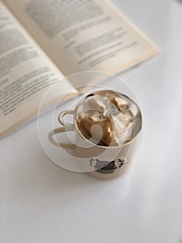 White Ceramic Mug Near an Open Book on Table