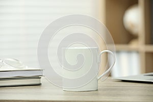 White ceramic mug and notebooks on wooden table indoors