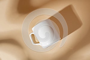 White ceramic mug on peach color surface close up photo