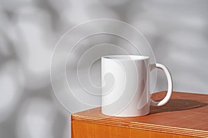 White ceramic mug on peach color surface close up photo