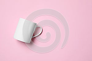 White ceramic mug on pink background, top view. Space for text