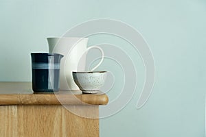 White ceramic mug and tea cup on nature wood table with vintage blue wall for food drink and interior background