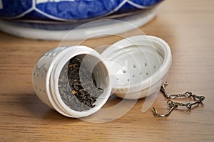White ceramic open tea strainer with dried Chinese Kee Mun tea leaves close up