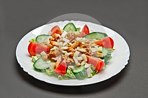 White ceramic plate with fresh tomatoes, cucumber, celery, lettuce and meat salad