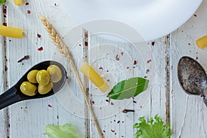 White ceramic plate surrounded by italian tortiglioni pasta, bay leaves and other ingredients.