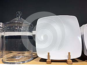 White ceramic plates on shelf in a store. Designer ceramic plates with a pattern. Table setting, tableware and eating concept