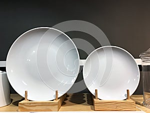 White ceramic plates on shelf in a store. Designer ceramic plates with a pattern. Table setting, tableware and eating concept