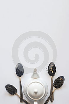 White ceramic tea pot and various dried teas on the white background. Flat lay view. Space for your text