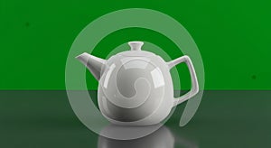 A white ceramic teapot sits centered on a reflective gray surface against a bright green