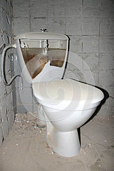 A white ceramic toilet bowl water closet, flush toilet, lavatory full of ice in old house cottage