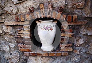 White ceramic vase with painted flowers in antique wall niche