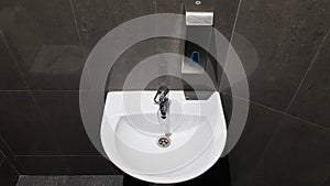 White ceramic washbasin with chrome faucet in the toilet with gray tile