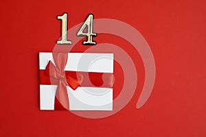 White certificate with red bow and number 14 over it on the red background. Romantic love letter for the Valentine`s day concept