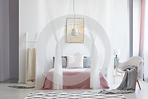 White chair in canopy bedroom