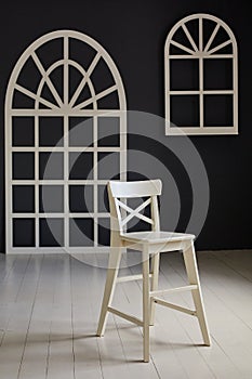 White chair on dark background.The wall is decorated with details in the form of arched doors and arched Windows