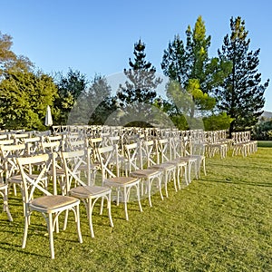 White chairs arranged for a sunny outdoor wedding